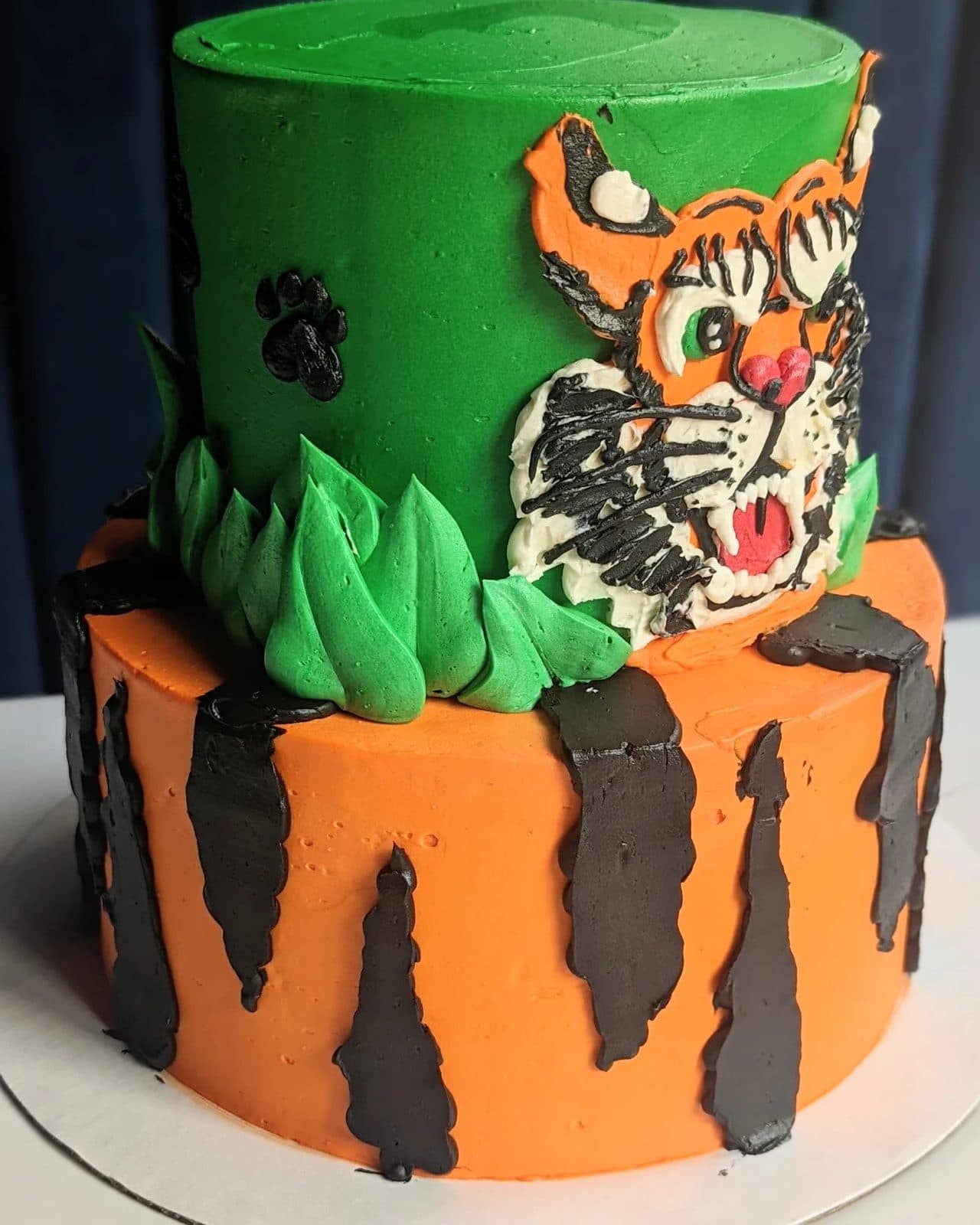 A slice pulled out to show horizontal orange, black, and cream stripes under the blue frosting, with the tiger on top.