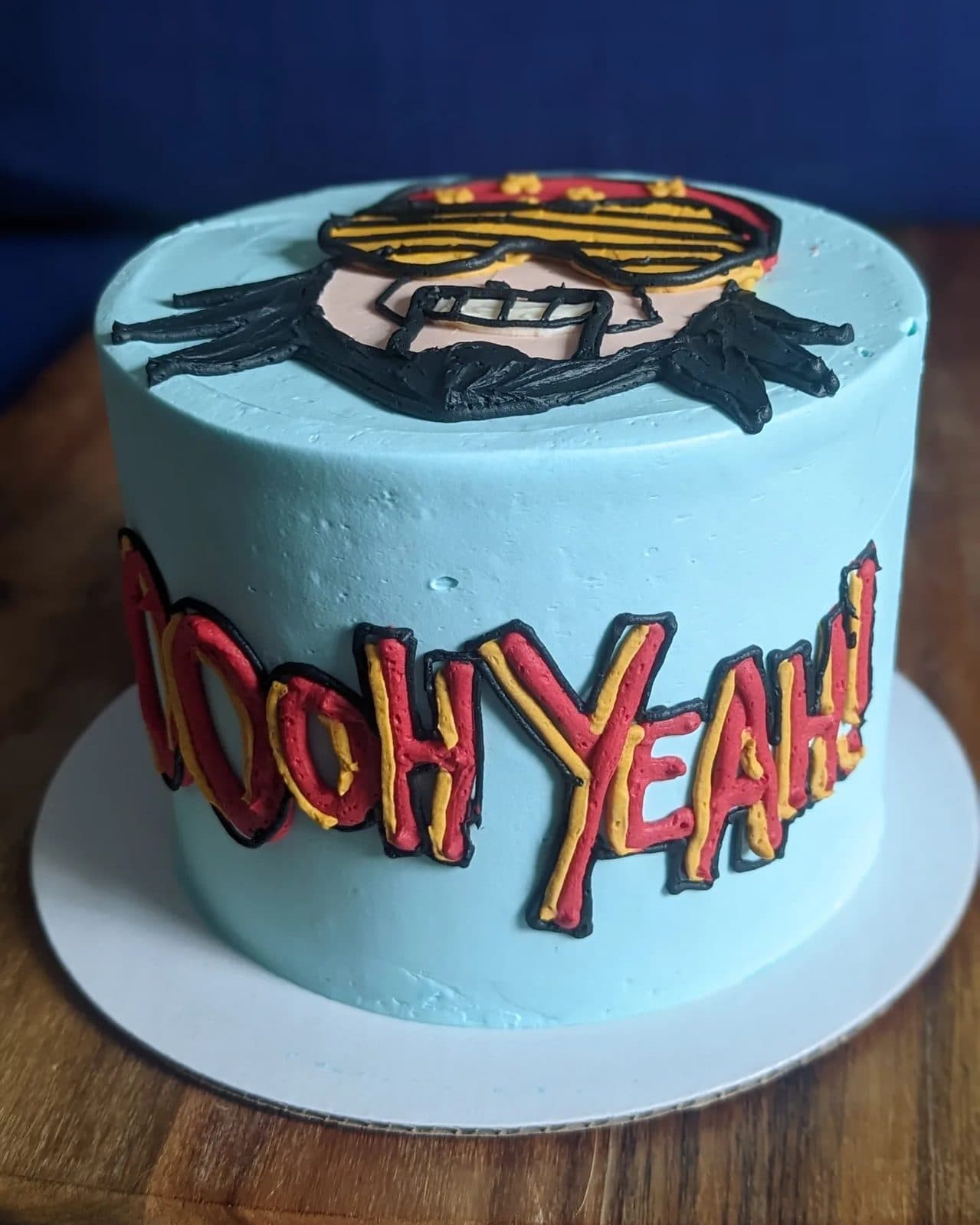 Closer view of the Macho Man face, sunglasses, and cowboy hat piped in buttercream.