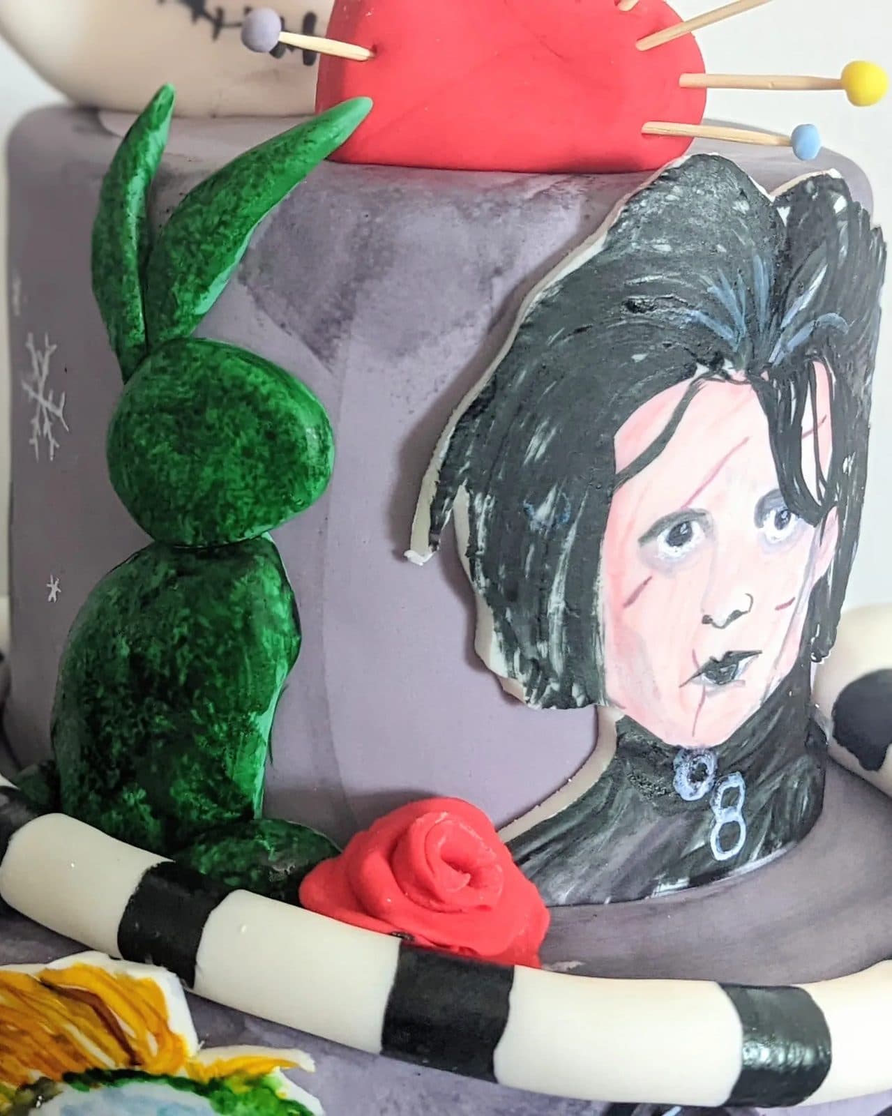 A darker side view of the same cake, tall black drips and curls against white frosting.