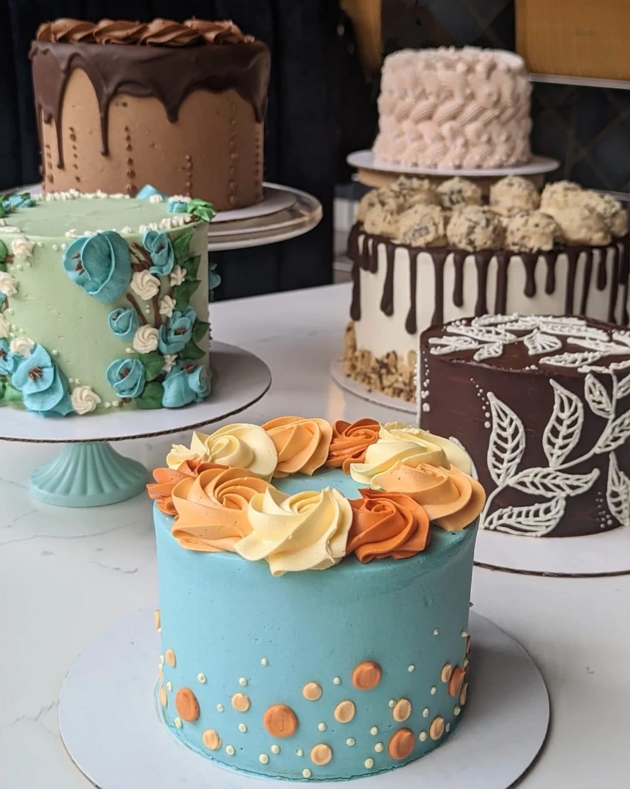 A pink drip cake topped with a buttercream flower bouquet.